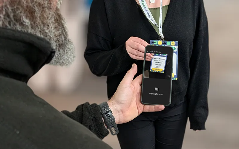 A man using the ContactScanning app on their smartphone to scan the badge a woman is wearing